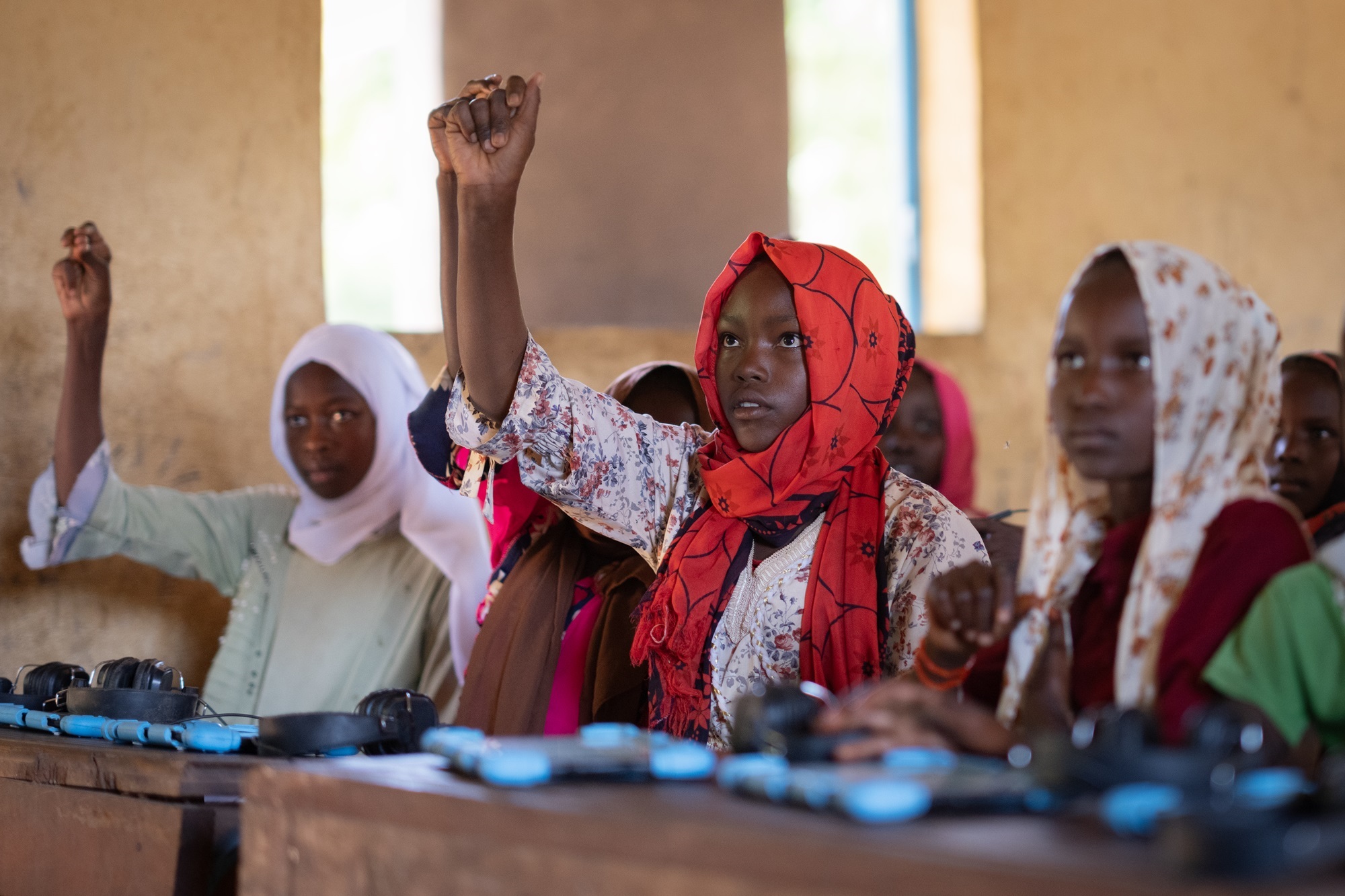 14-year-old student Sumaya Abdel Rahman Mahmoud Mohamad, centre, raises her hand during a lesson, part of an EdTech program developed by War Child named ‘Can’t Wait to Learn’, at a school in Djabel Refugee Camp, Eastern Chad. (Michael Knief/Global Partnership for Education)